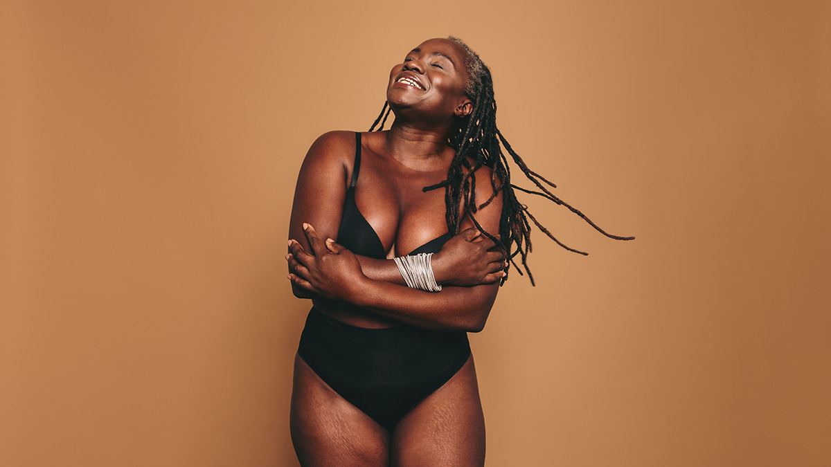 A beautiful, happy African-American woman in her underwear showing off her real glowing skin with stretch marks